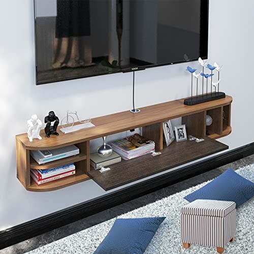 Modern floating shelf with decorative items and books under a wall-mounted TV.