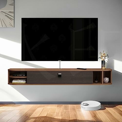 Modern living room with wall-mounted TV, floating shelf, and robotic vacuum.